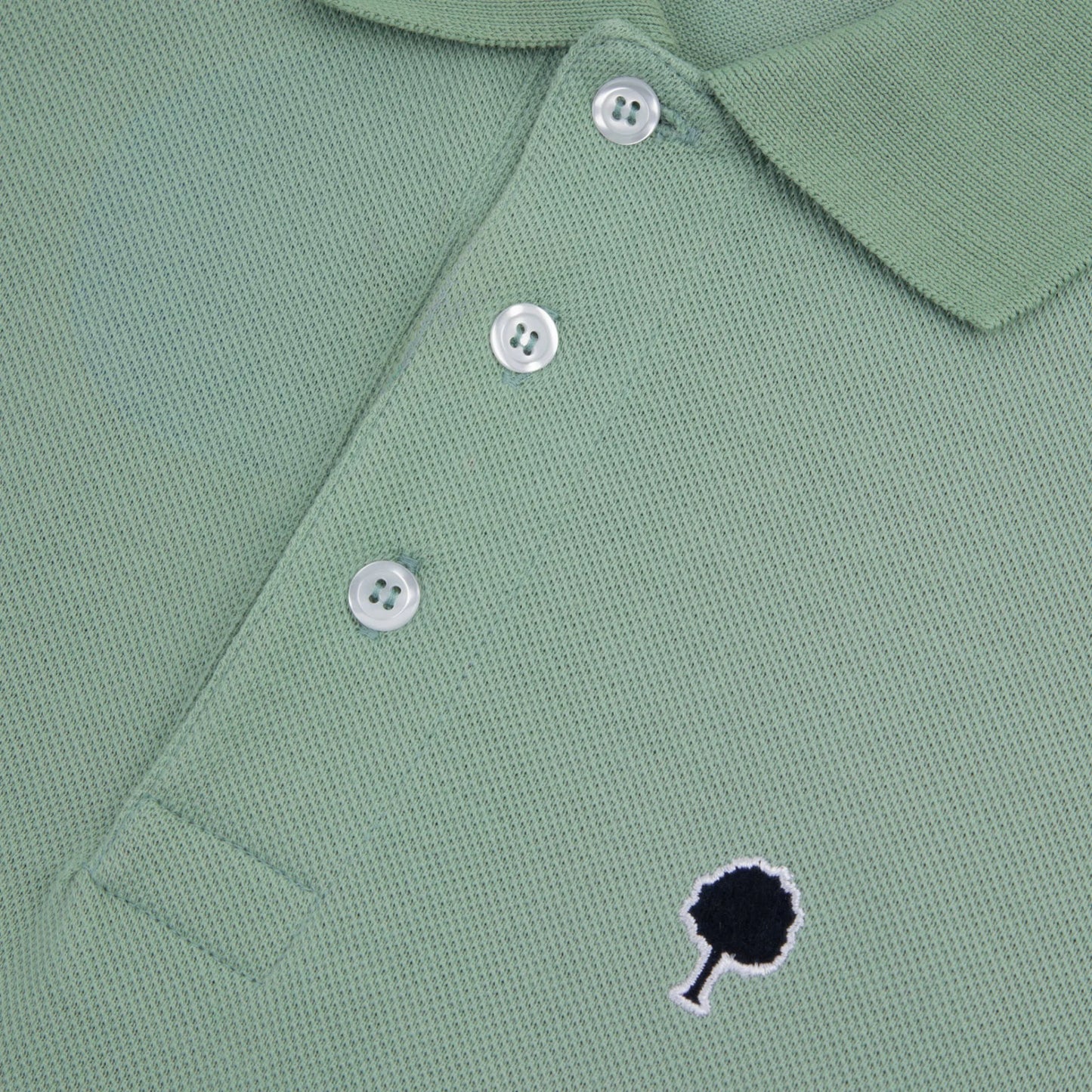 Zoom sur le logo brodé du polo piqué vert clair FAGUO en coton recyclé