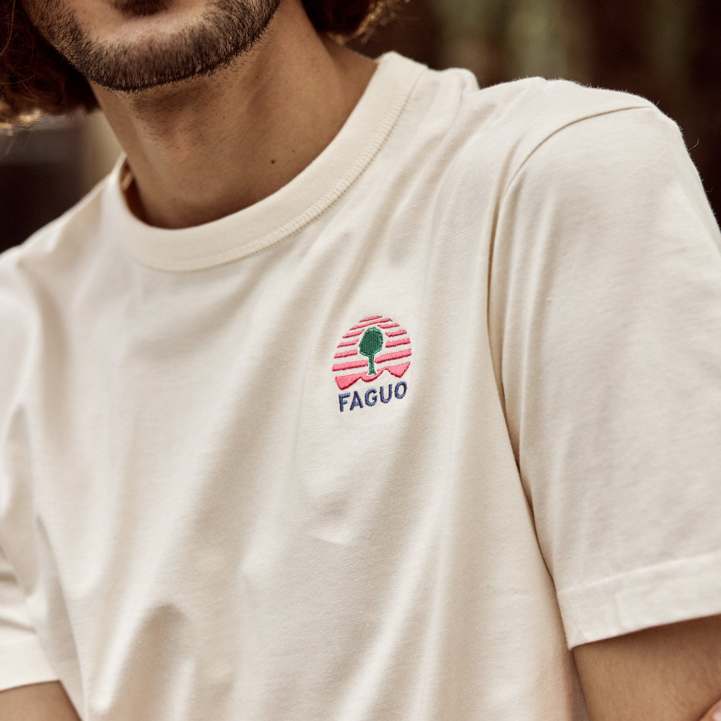 T-shirt écru FAGUO avec un chino beige et des baskets blanches, look urbain d'été
